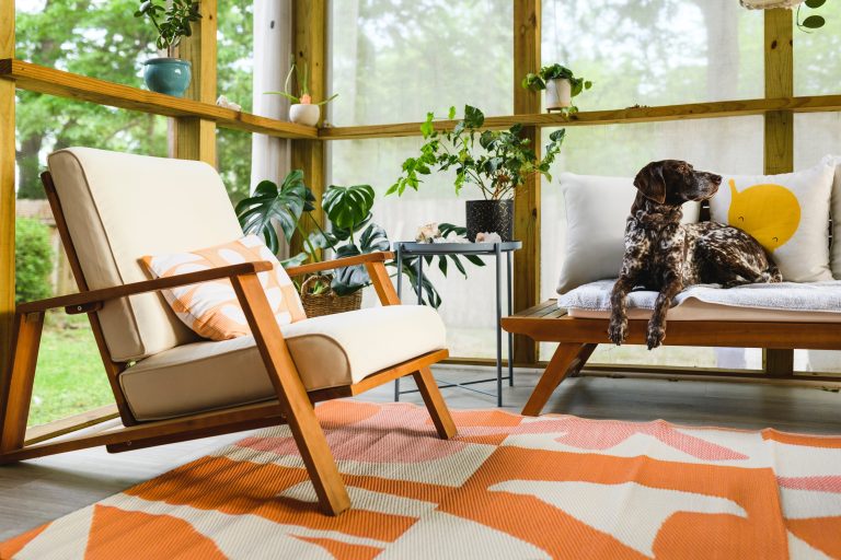 Cozy and stylish sunroom constructed by Bastos Construction, featuring modern furniture, a colorful area rug, and a view of the lush outdoors, perfect for relaxation and enjoying nature.